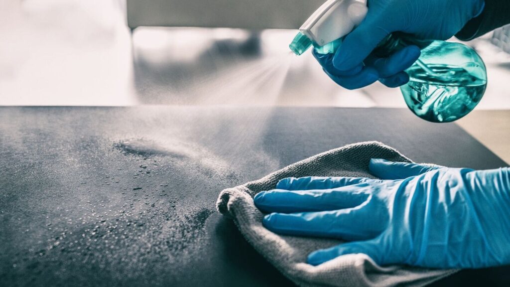 a person spraying a surface with a rag